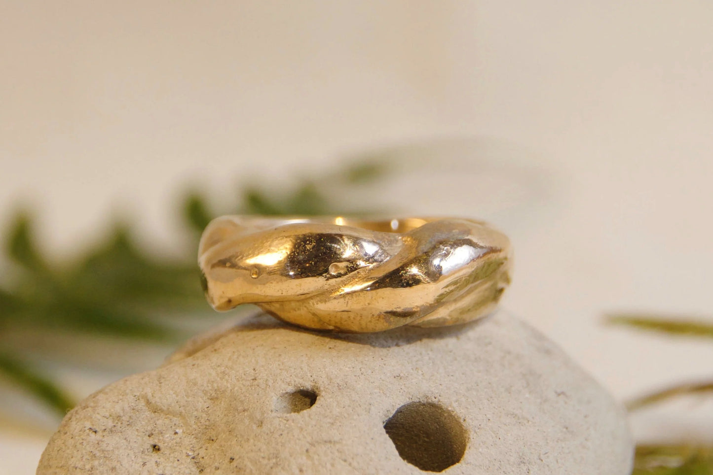 Bronze ring on a white stone with green leaves in the background