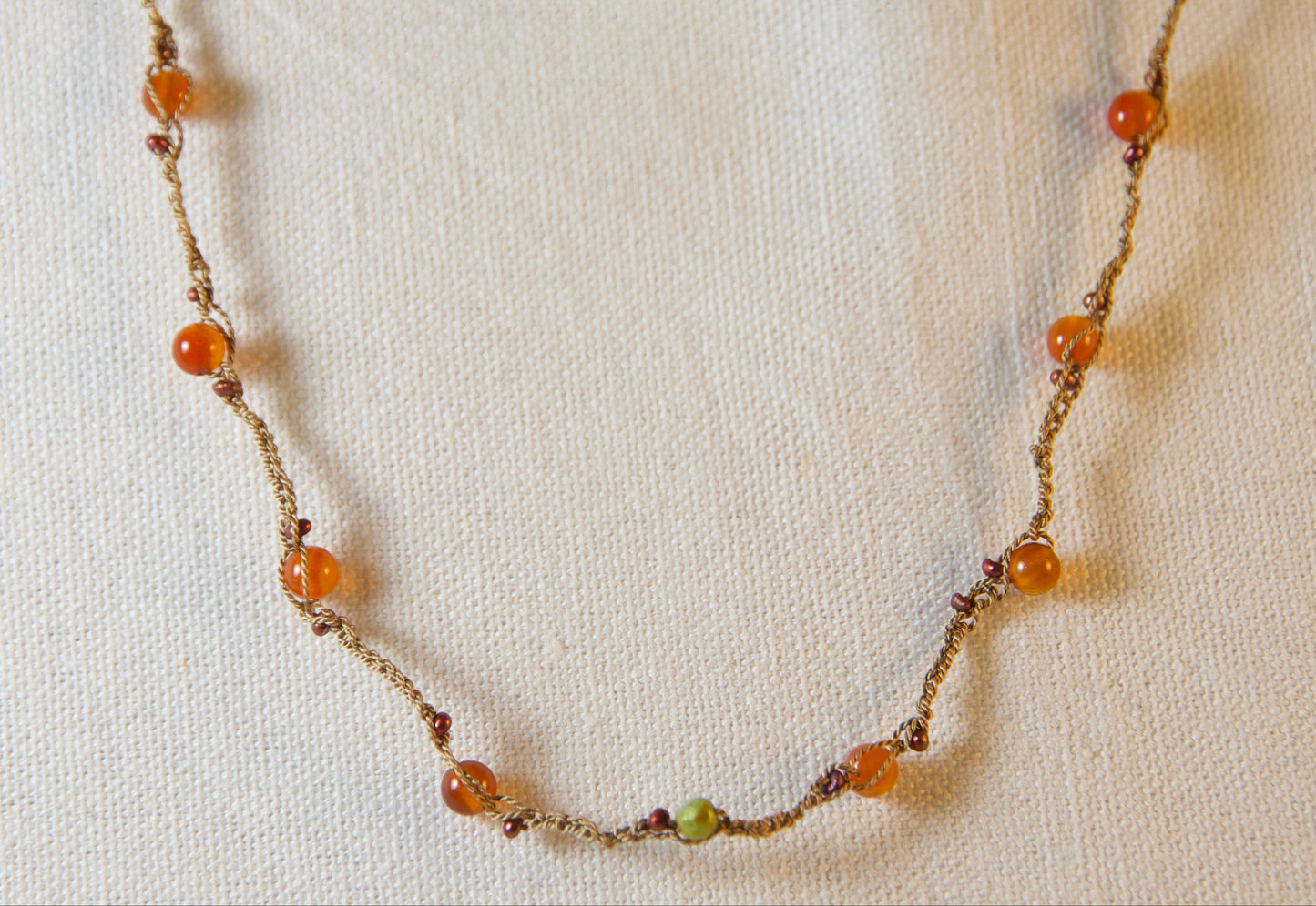 Necklace with multicolored beads on a textured beige background