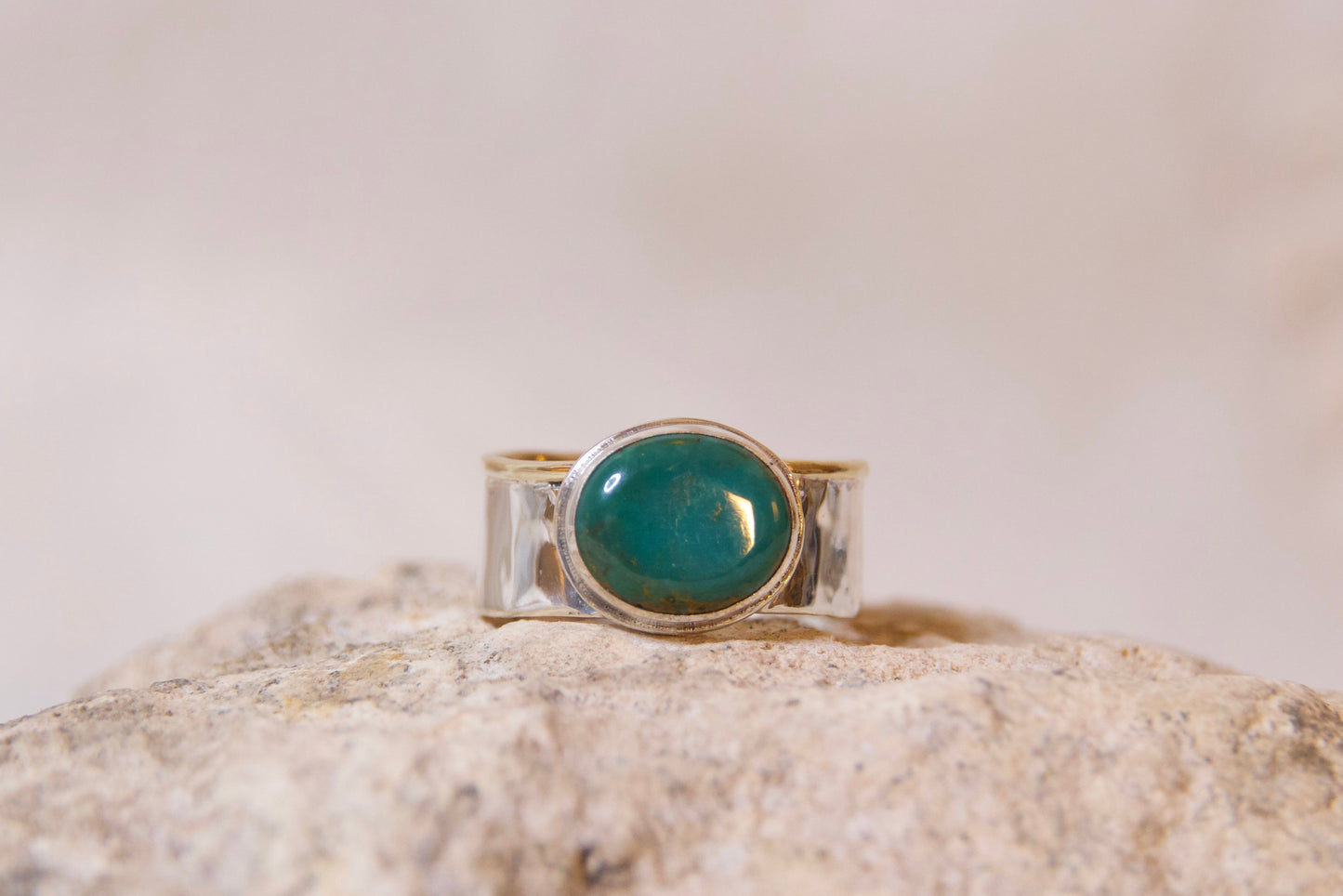 Silver ring with a green stone on a textured surface