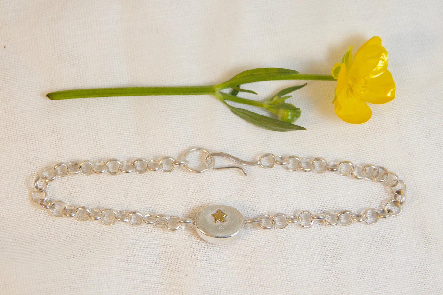 Silver bracelet with a yellow flower on a white background