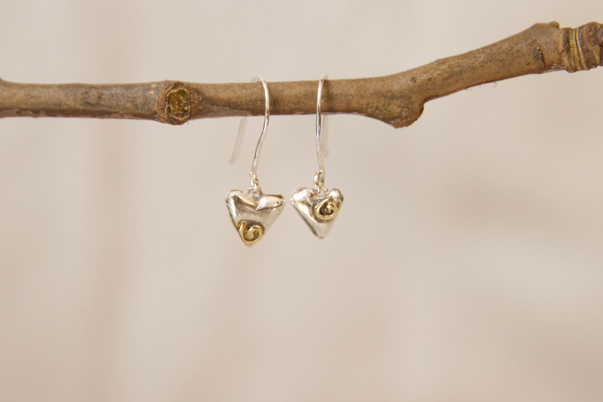 Handcrafted sterling silver hearts with hand sawed brass swirl designs. 