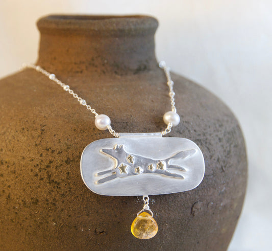 Necklace with a pendant on a textured brown vase against a white background