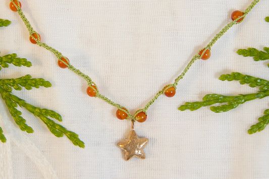 Necklace with green beads and a star pendant on a white fabric background