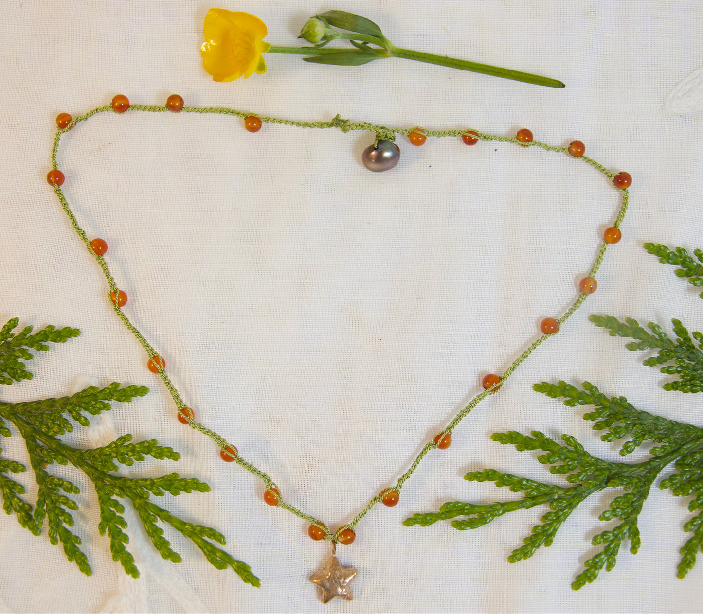 Necklace with green leaves and a yellow flower on a white background