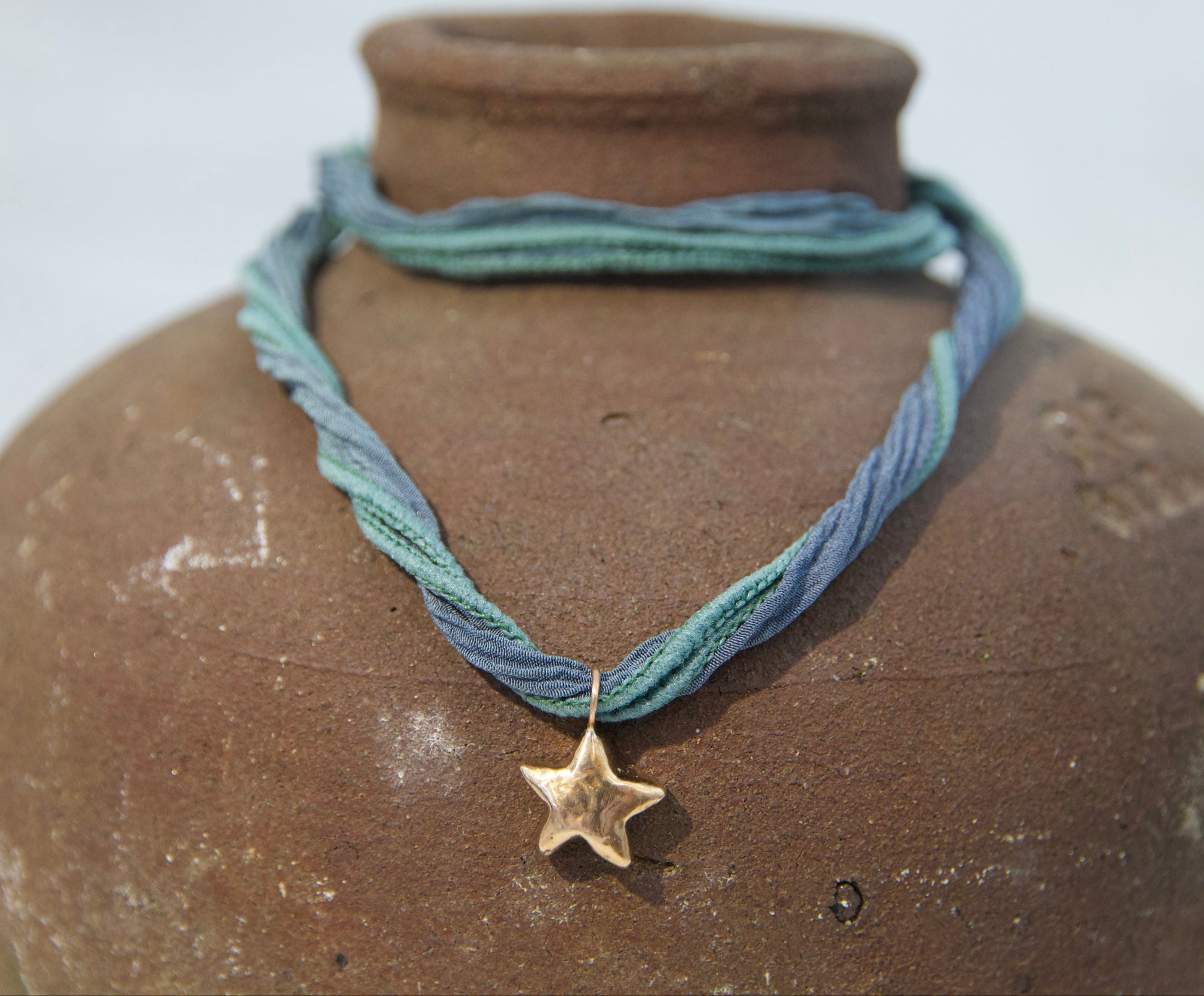 Hand crafted whimsical golden colored star necklace on a brown background 