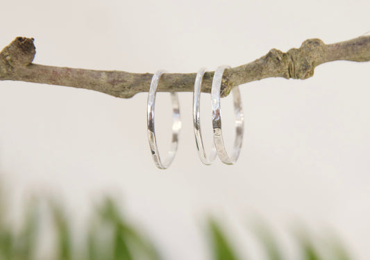 Silver bands hanging from a branch with a blurred natural background