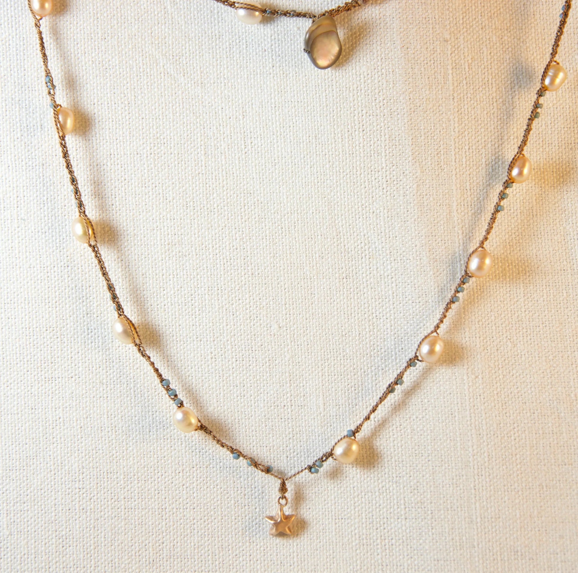 Necklace with bronze pendant and small pearls on a white background