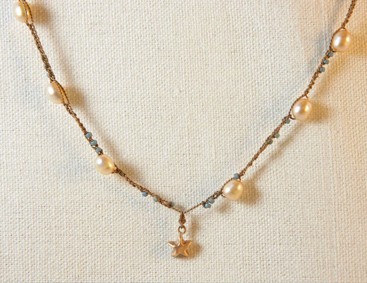 Necklace with pearls and a small pendant on a light background