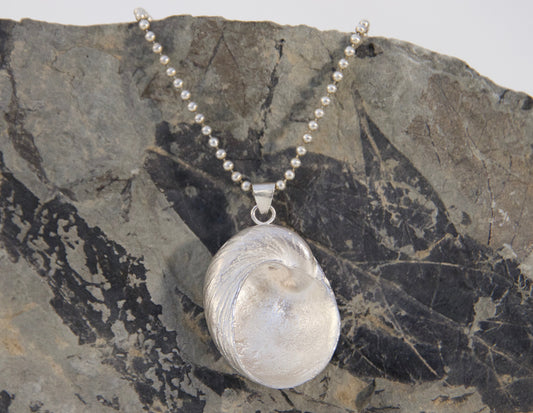 Silver pendant necklace on a rocky surface