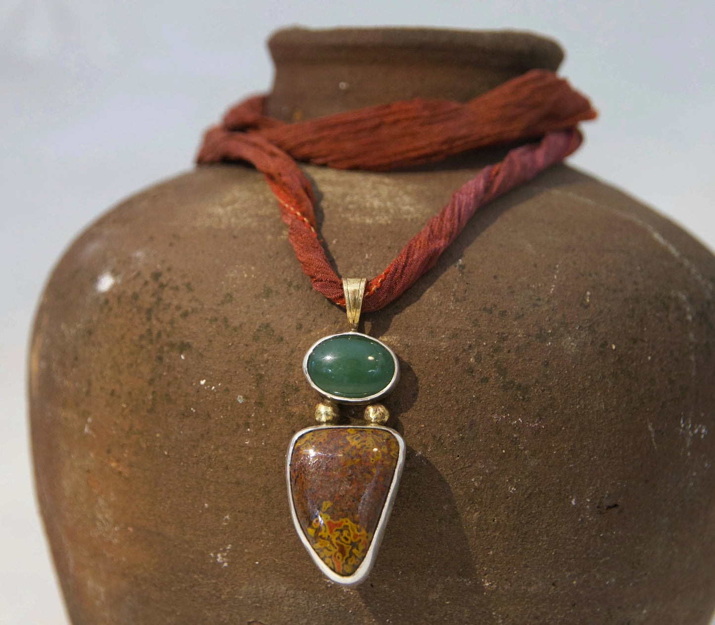 Sterling silver and brass necklace on a silk necklace