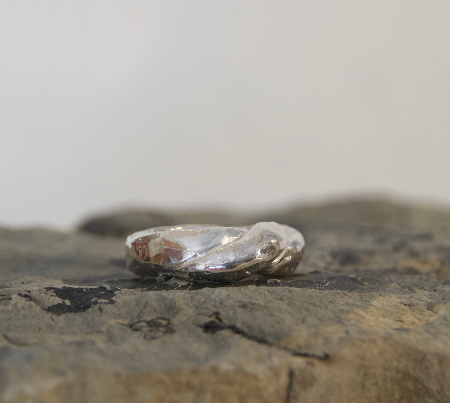 Silver ring on a textured stone surface with a plain background