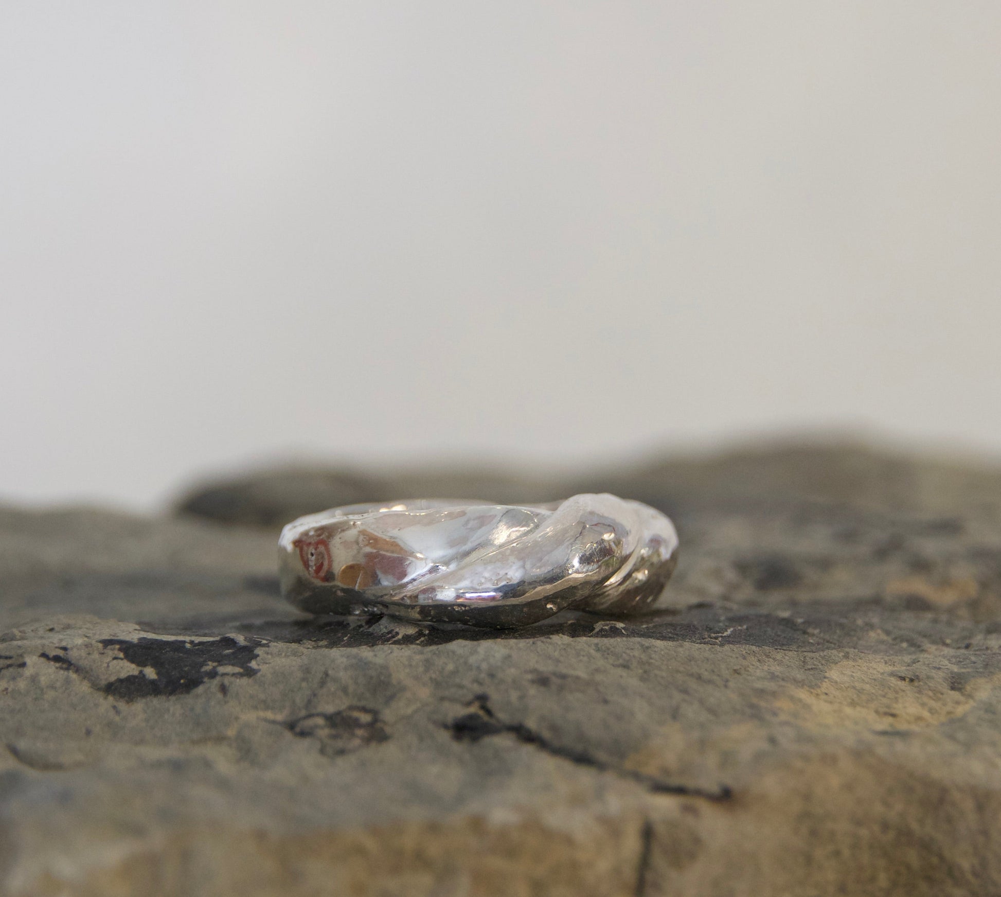 Silver ring on a textured stone surface with a plain background