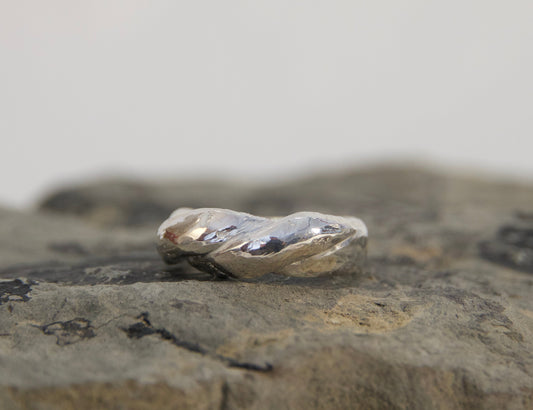 Silver ring on a textured stone surface with a blurred background