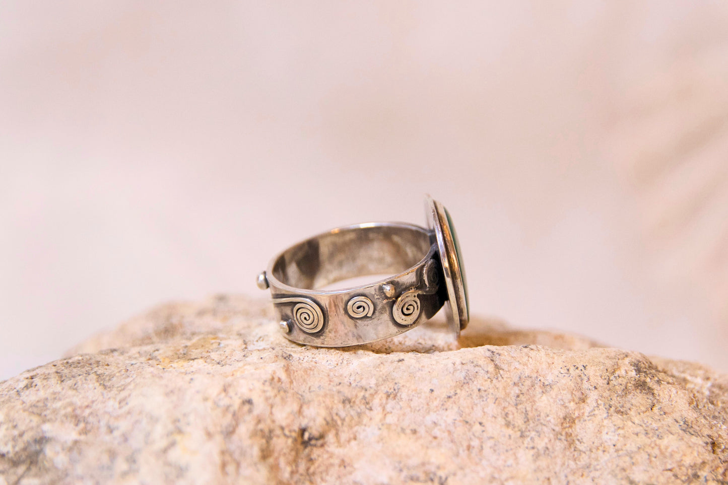 Silver ring with engraved design on a rock