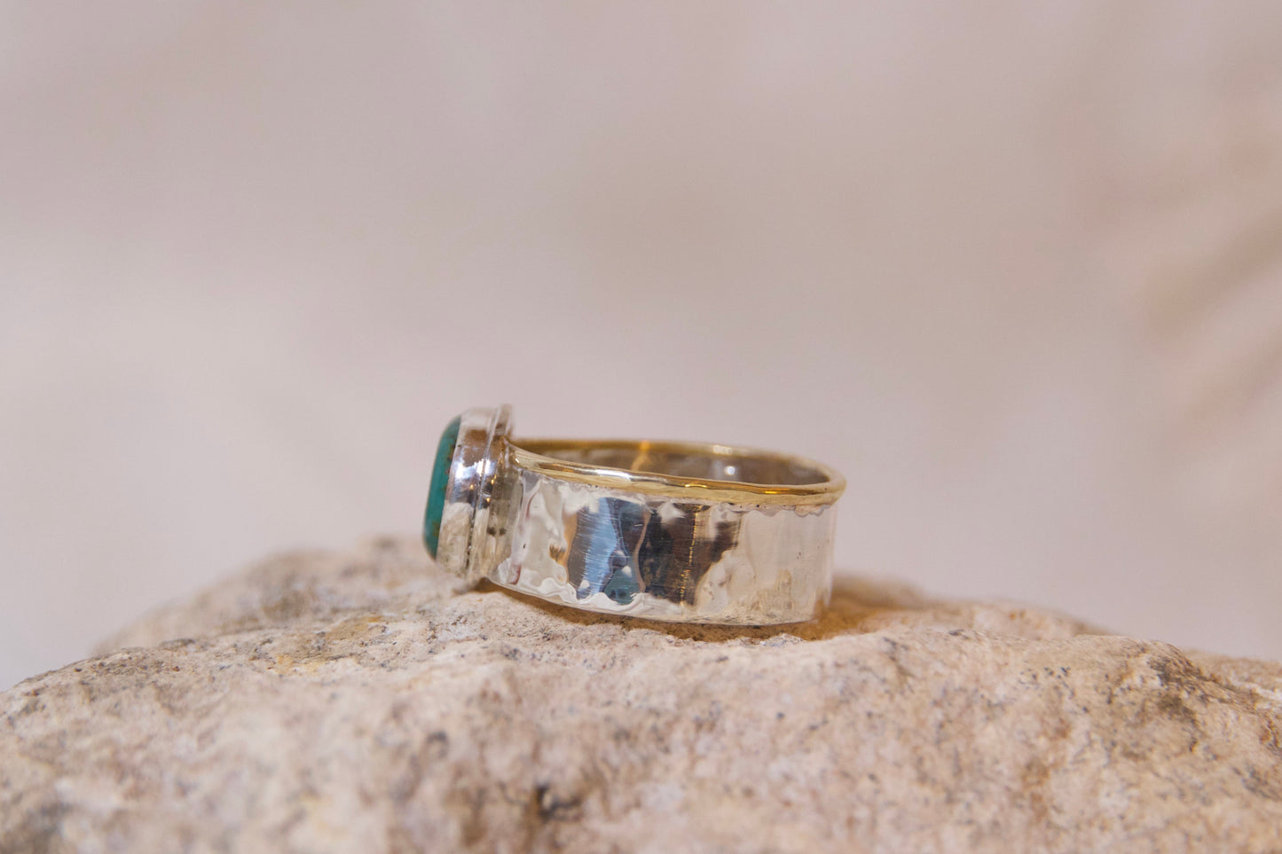 Gold ring with a green gemstone on a textured surface